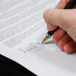 Close-up of a hand signing a separation agreement document with a fountain pen