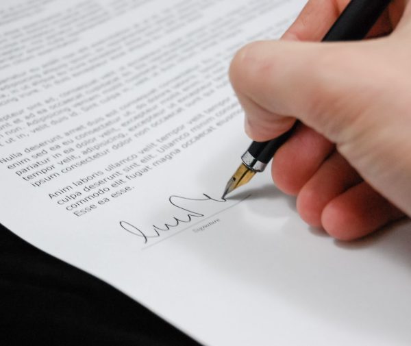 Close-up of a hand signing a separation agreement document with a fountain pen