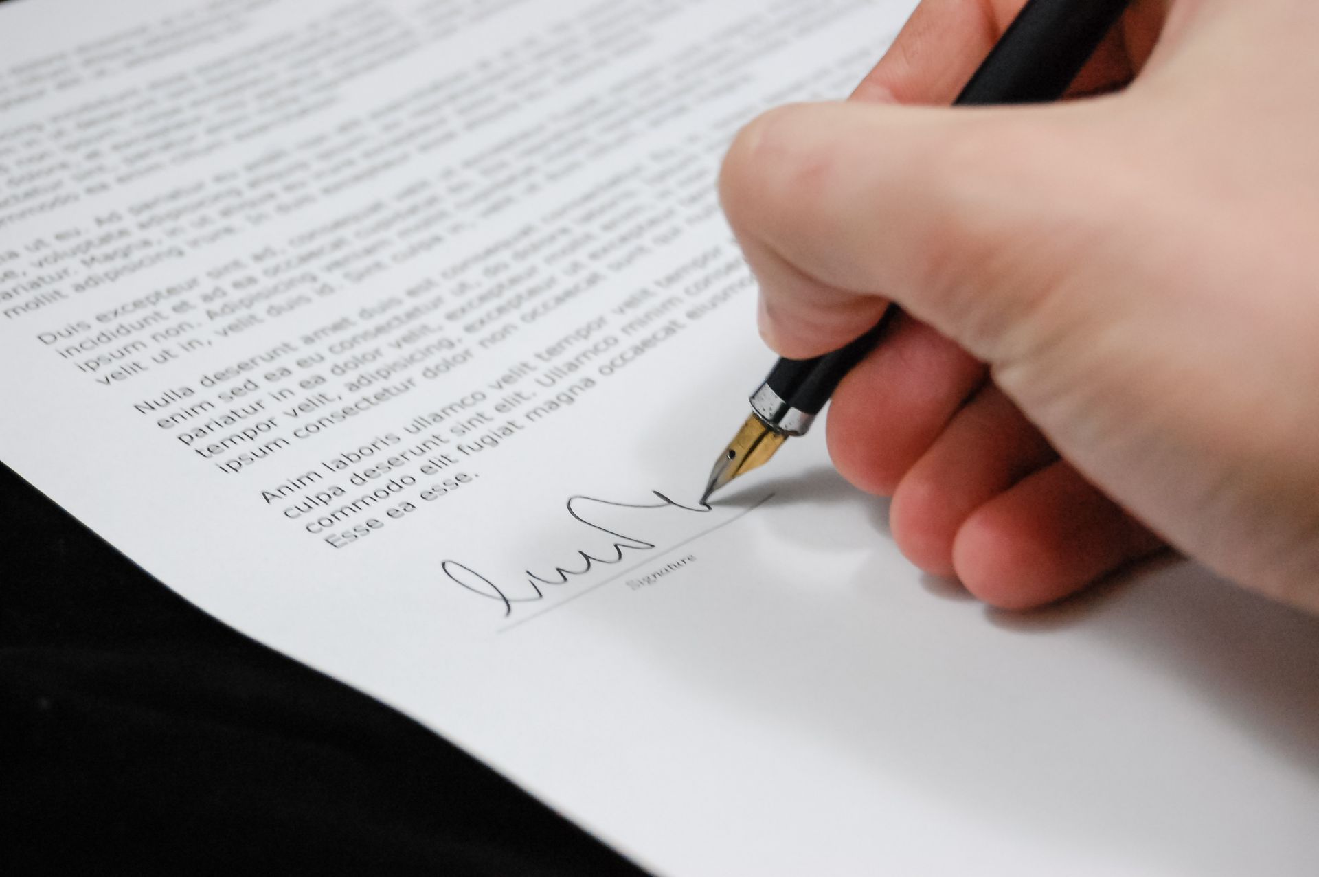 Close-up of a hand signing a separation agreement document with a fountain pen